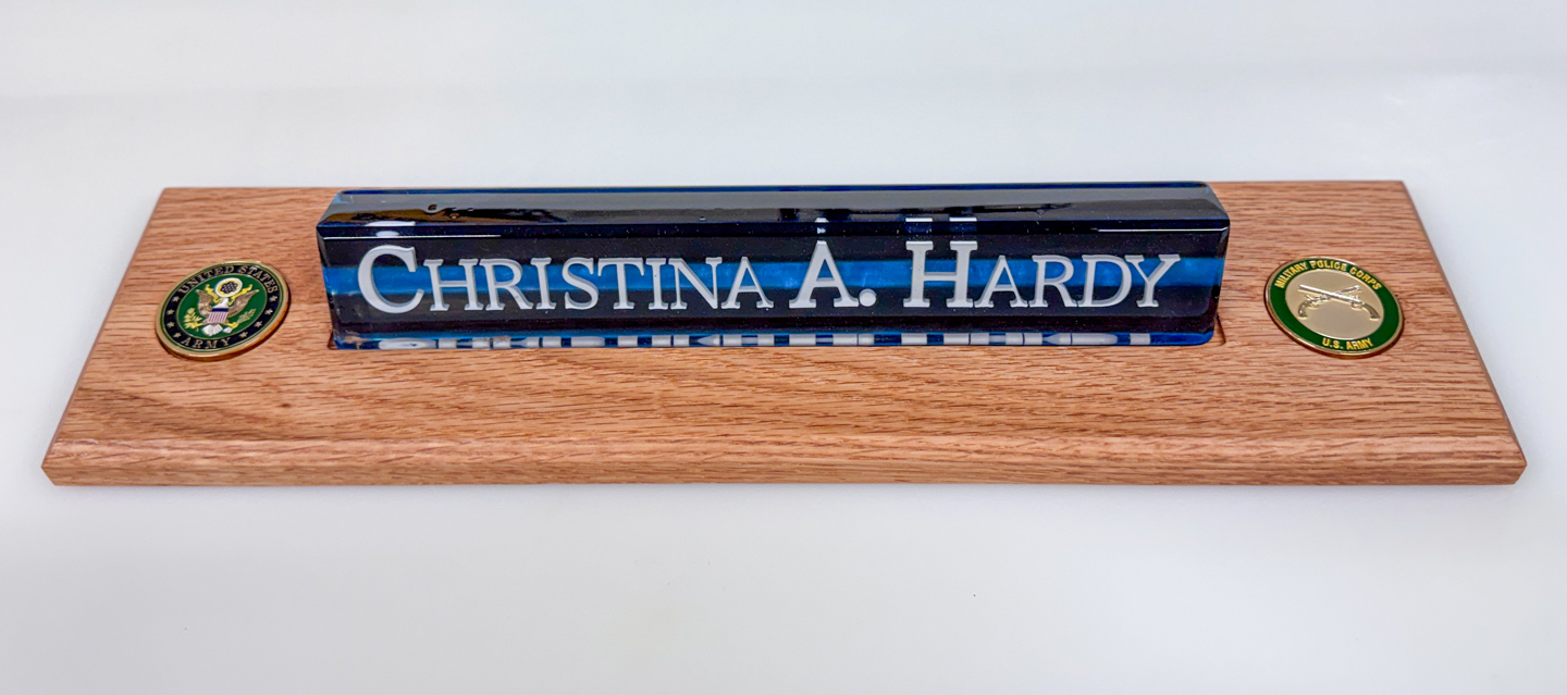 Personalized desk nameplate on a wood base A custom resin desk nameplate with the name Christina A. Hardy on a wooden base, flanked by two military-themed challenge coins.