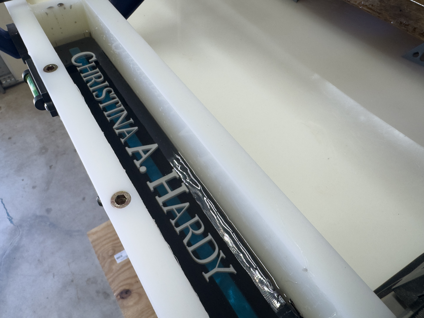 Custom epoxy nameplate curing in a mold A custom epoxy nameplate with raised lettering sits inside a mold during fabrication.