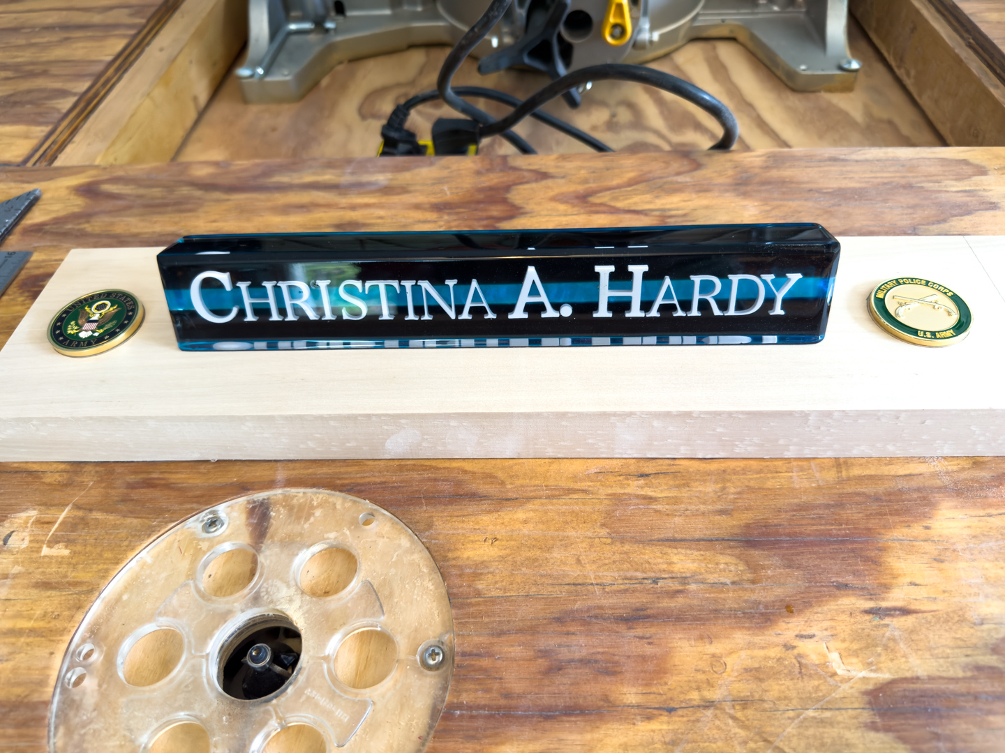 An epoxy nameplate with two challenge coins on a wooden desk