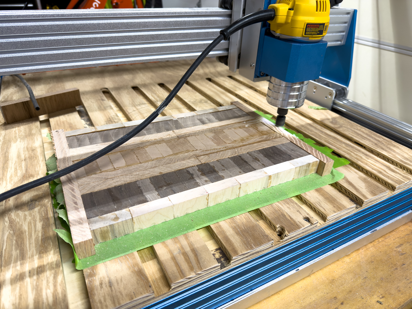 CNC machine shaping a wooden cutting board blank A CNC router machine mills a wooden cutting board blank on a worktable in a workshop.