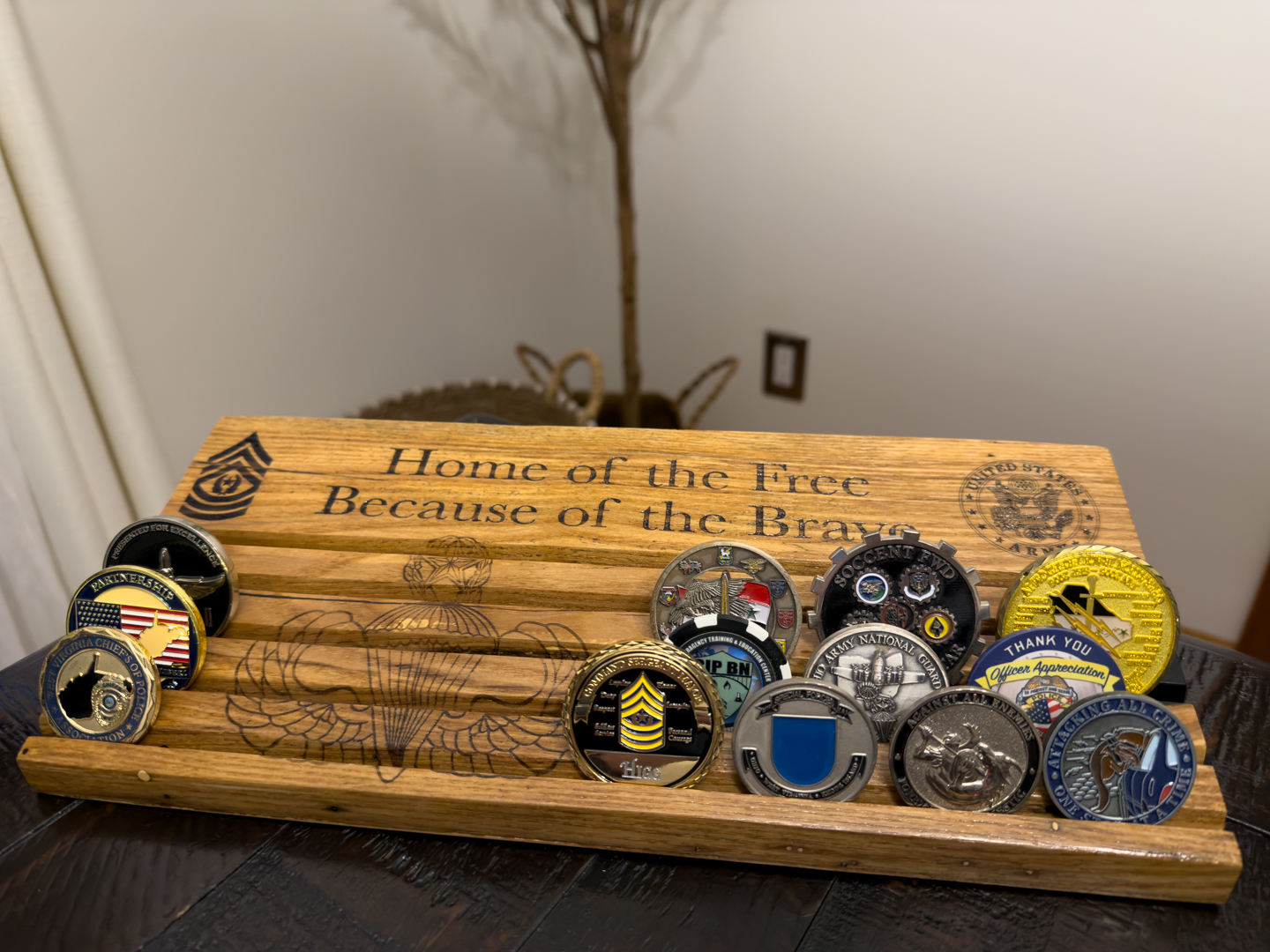 A wooden display holding a row of challenge coins on a dark table
