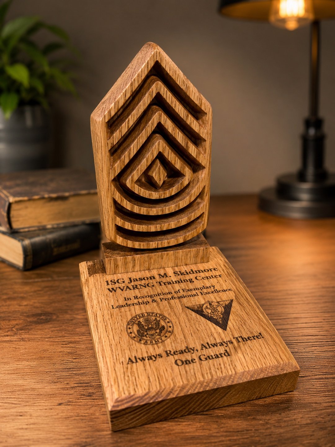 An engraved wooden recognition trophy with a stepped top and a metal emblem, standing on a desk