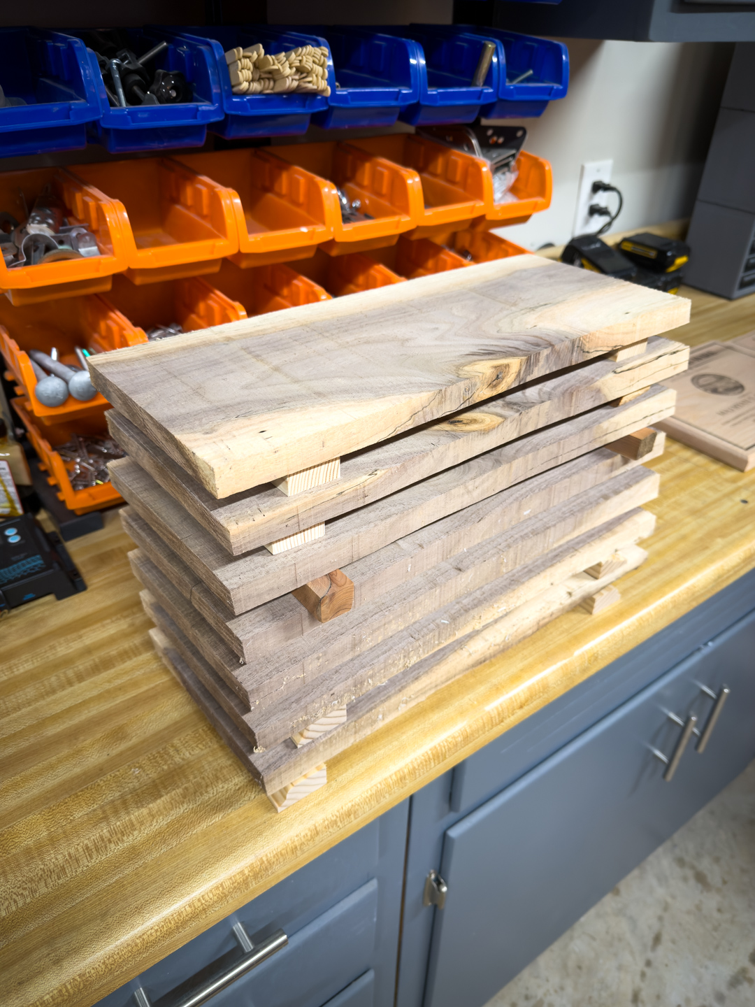 Stacked wood boards held with clamps on a shop workbench, waiting to dry