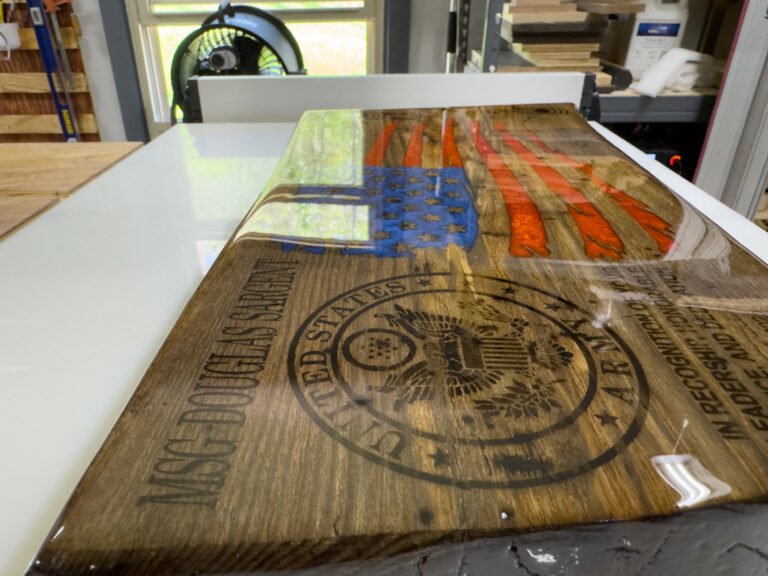 The engraved plaque covered in a glossy coat of clear epoxy on a white work table.