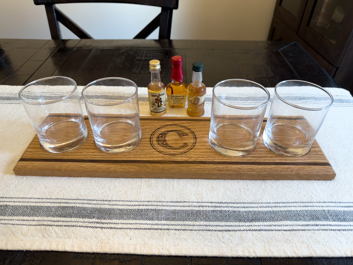 Oak whiskey flight board with four glass recesses and an engraved monogram
