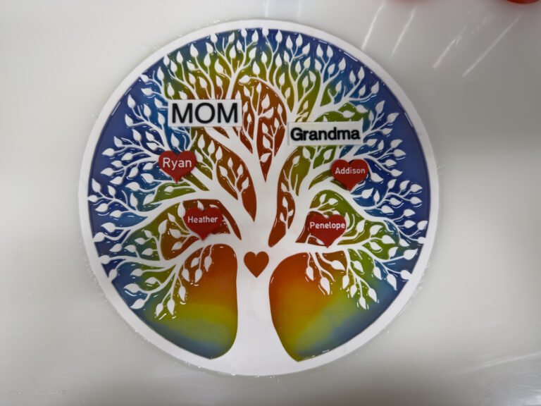 The tree of life with rainbow resin filling the openings, on a white mat.