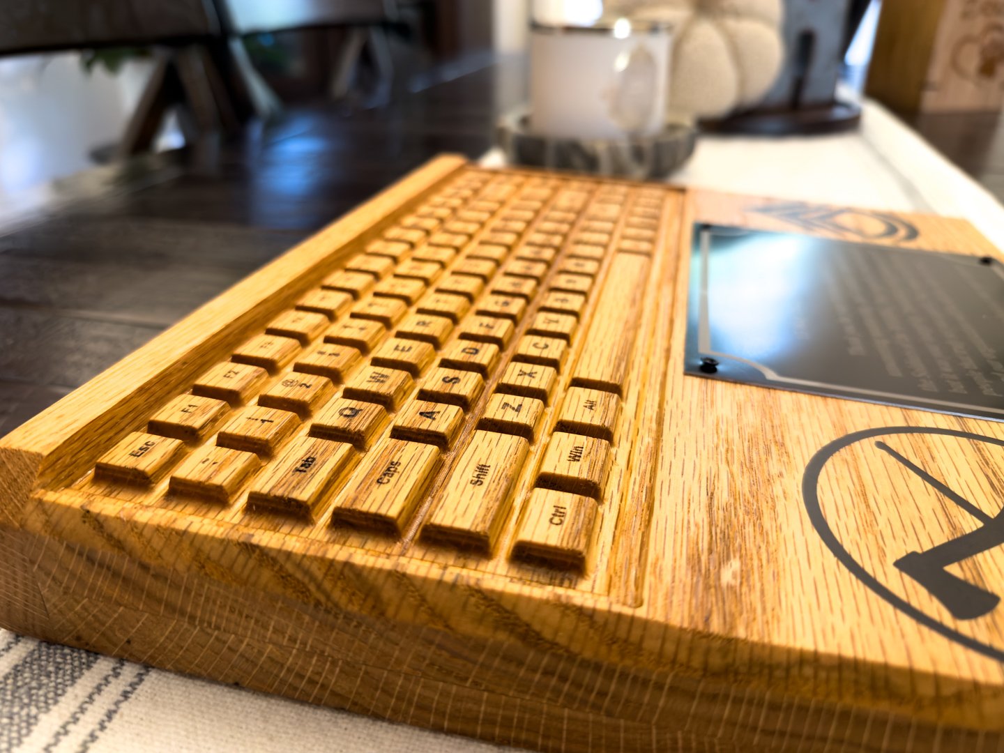 A finished wooden keyboard with a dark base and engraved front edge sitting on a tabletop.