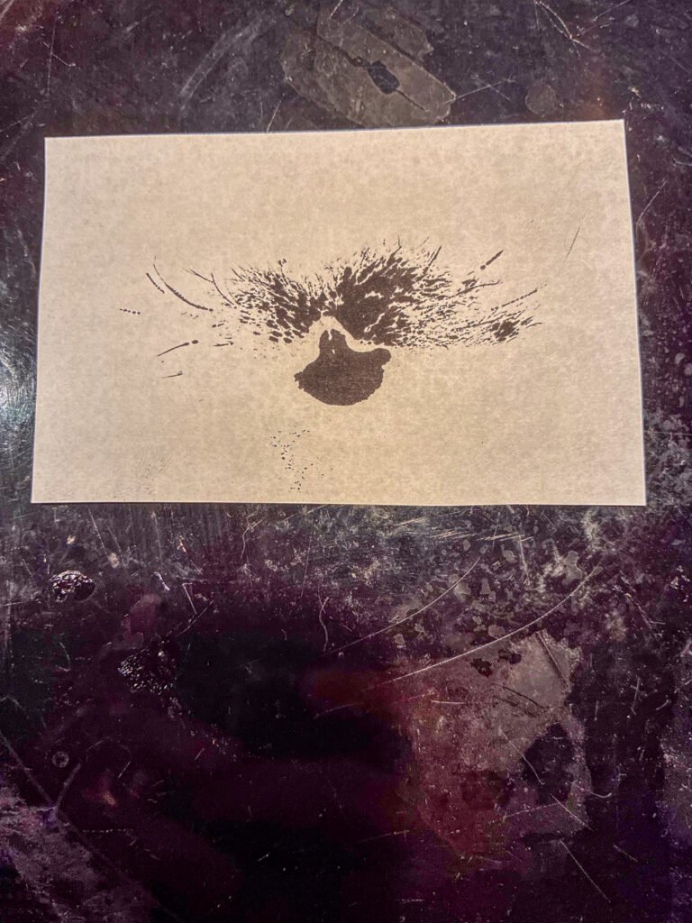 An ink print on a sheet of paper resting on a dark surface.