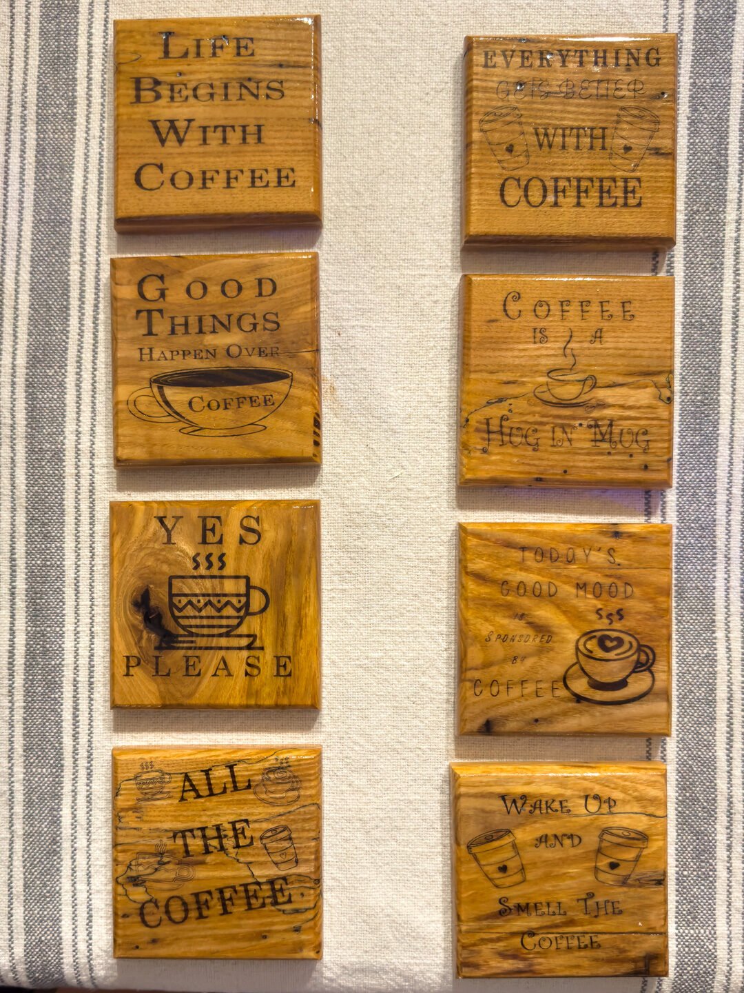 Engraved coffee wooden coaster set with eight coffee sayings displayed on a table