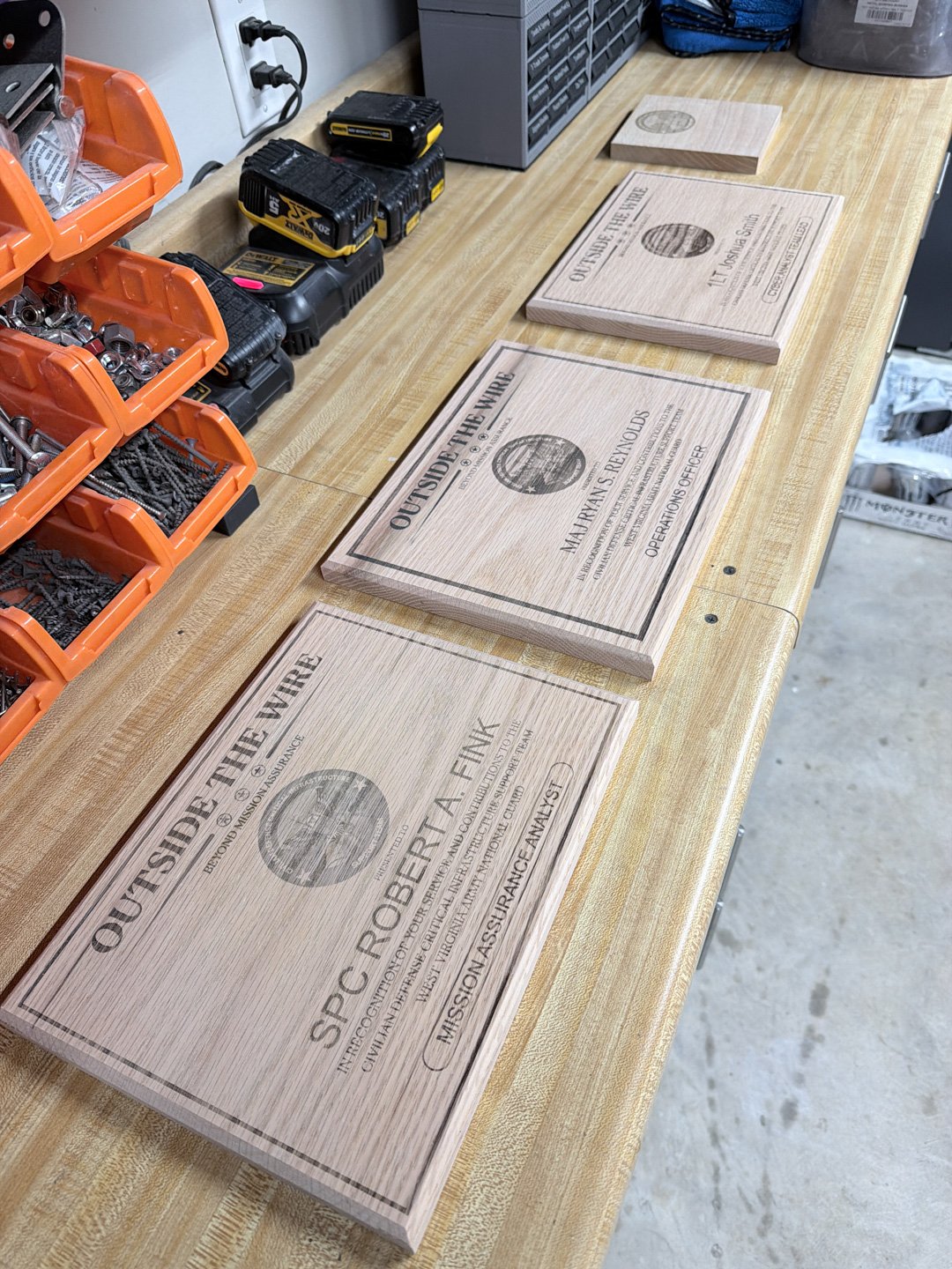 A row of laser-engraved wooden plaques laid out on a workshop bench