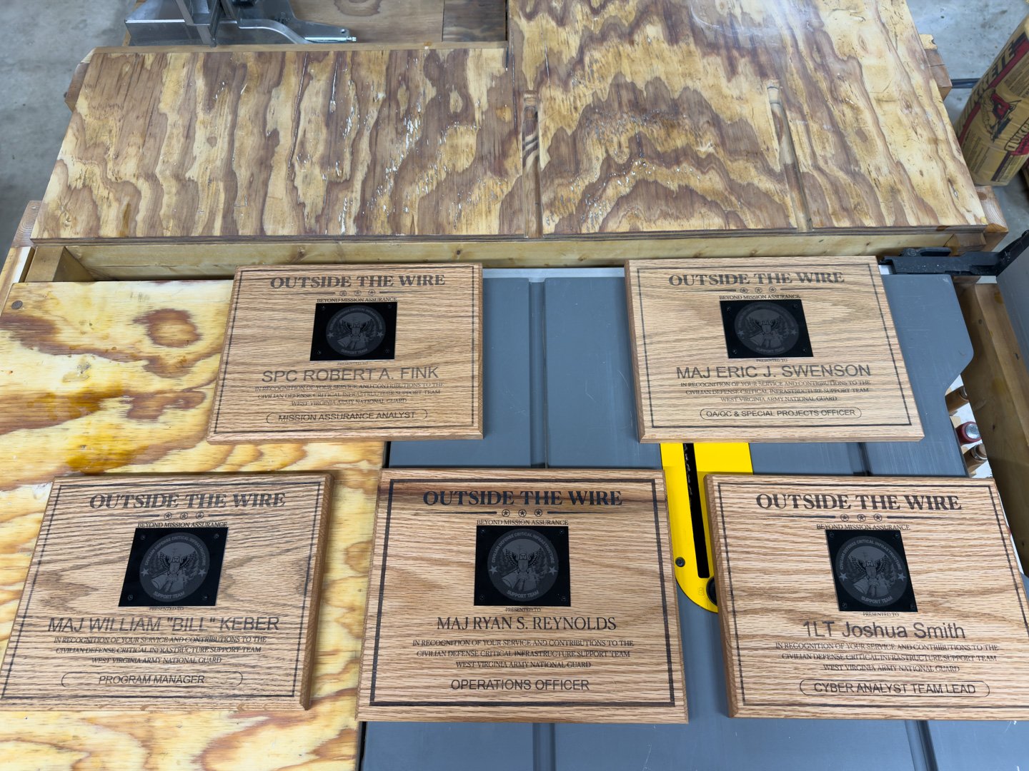 A set of matching engraved wooden plaques displayed together on a workbench