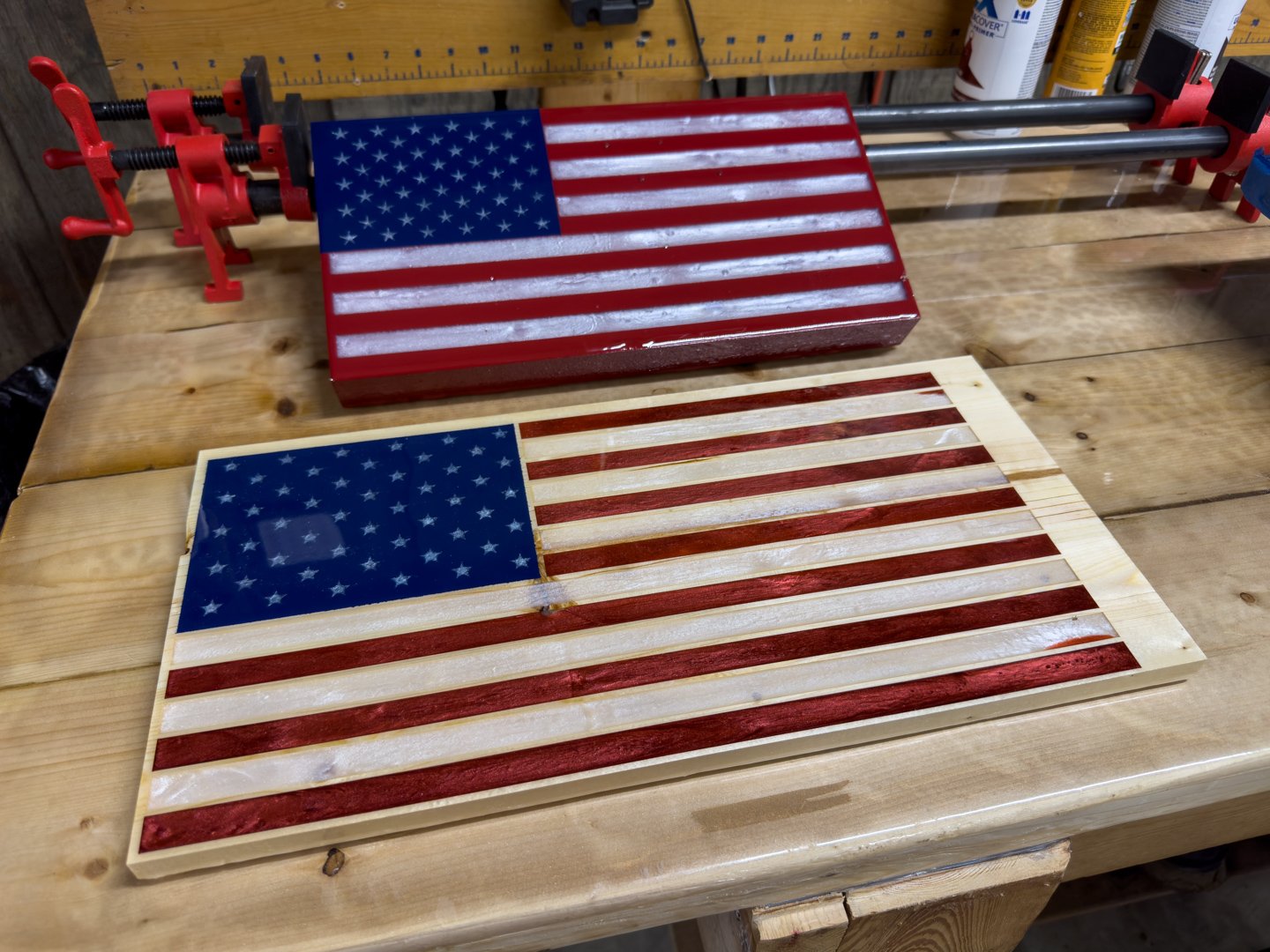 Two handmade wooden American flag plaques leaning on a workbench in the workshop