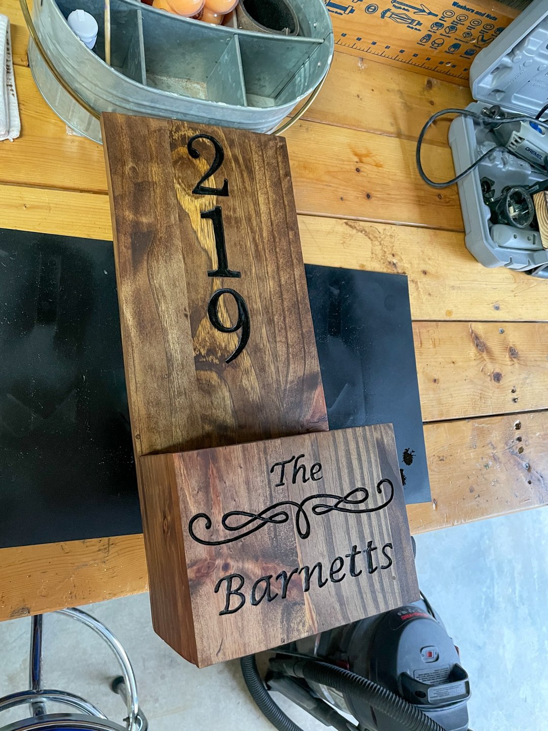 Close-up of a stained pine planter backboard with carved house numbers and a script family name