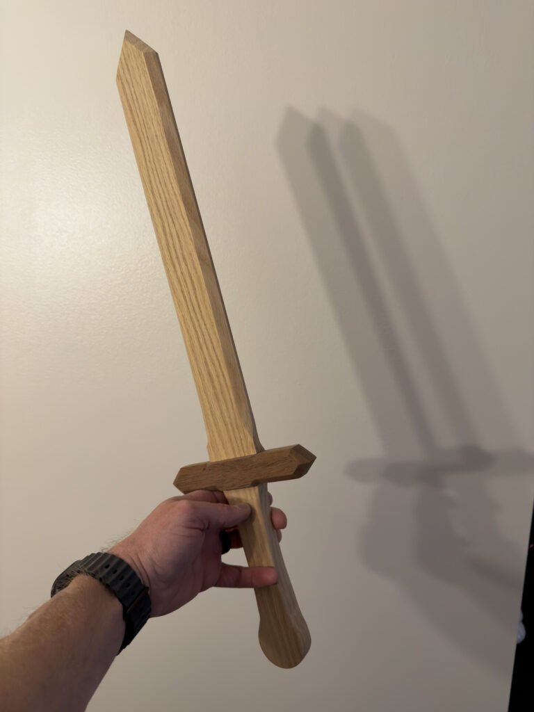 Oak blank for an engraved commemorative wooden sword, held by hand before engraving