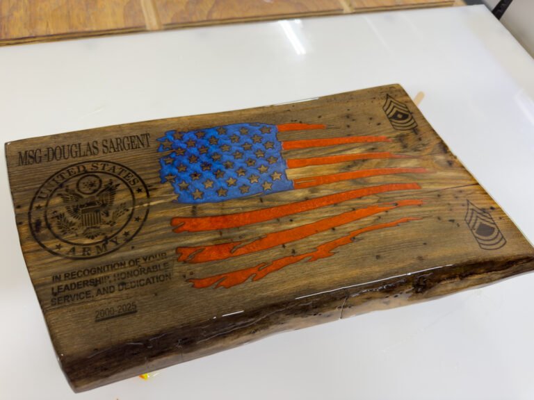 The engraved flag plaque under fresh glossy epoxy on a white work table.